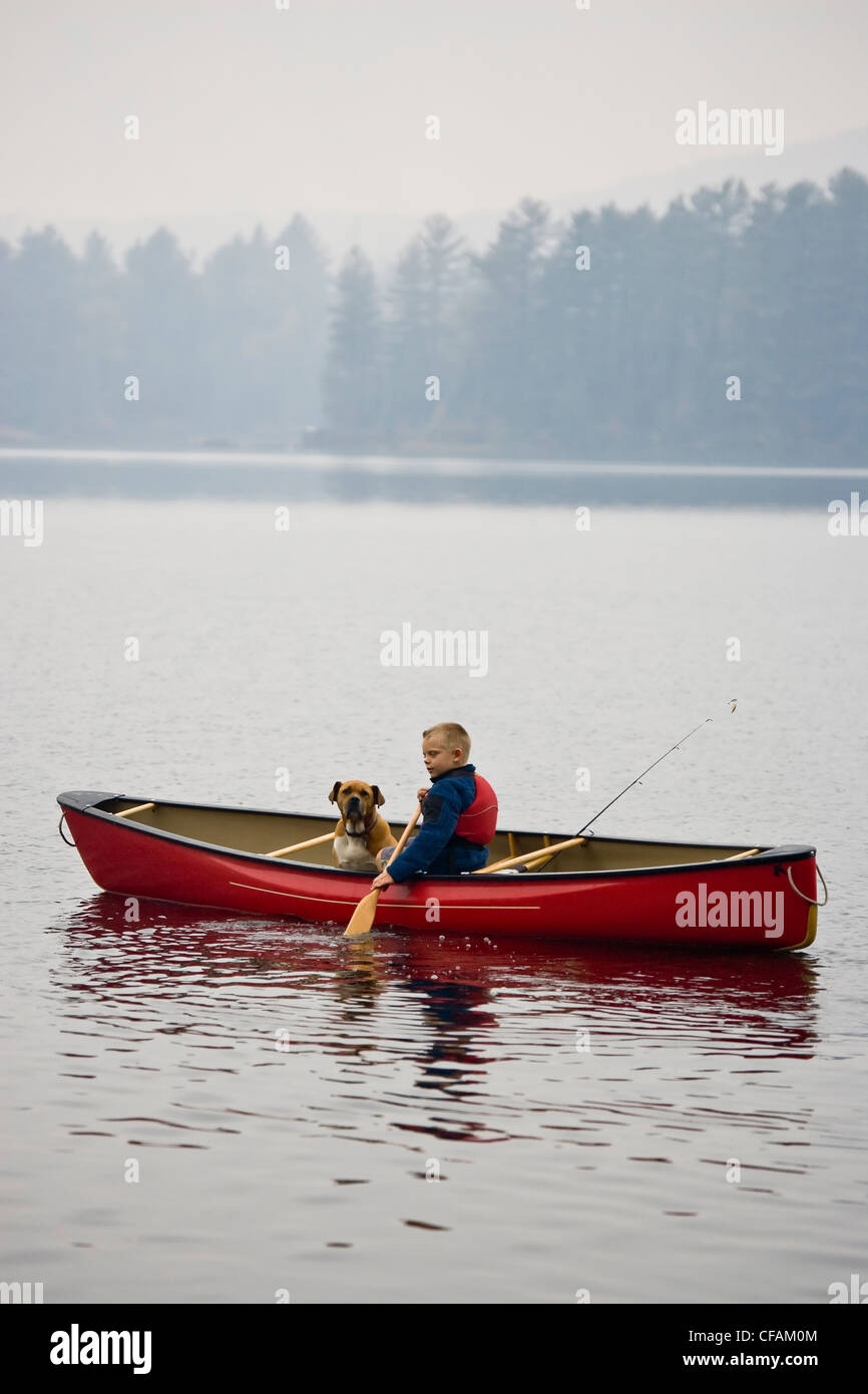 Junge Angeln mit Hund im Kanu auf Quelle See, Algonquin Provincial Park, Ontario, Kanada. Stockfoto