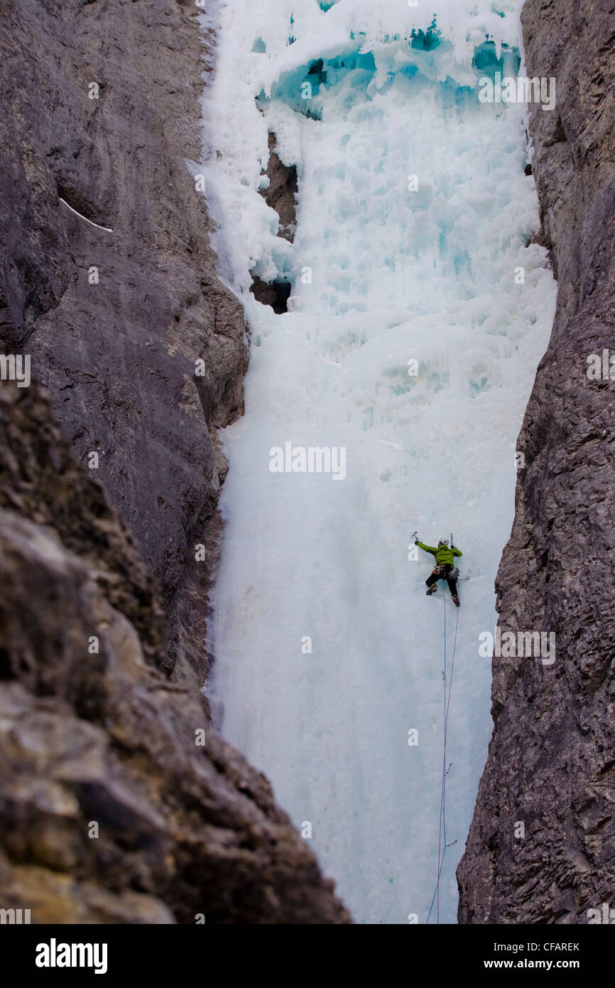 Ein Eiskletterer, in der Ferne, schwingt seine Axt ins Eis bei Ghost River, Alberta, Kanada Stockfoto Ein Eiskletterer, in der Ferne, schwingt seine Axt ins Eis bei Ghost River, Alberta, Kanada Stockfoto