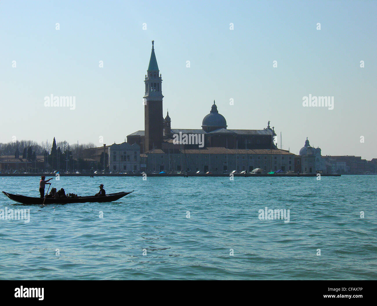 Ein Gondoliere, stehend auf einer Gondel führt Touristen vor San Marco, Venedig Stockfoto