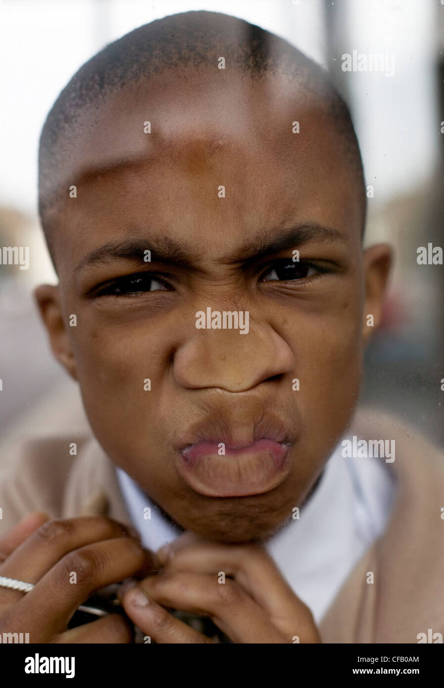 Junge mit Gesicht gegen eine Glasscheibe gedrückt. Stockfoto