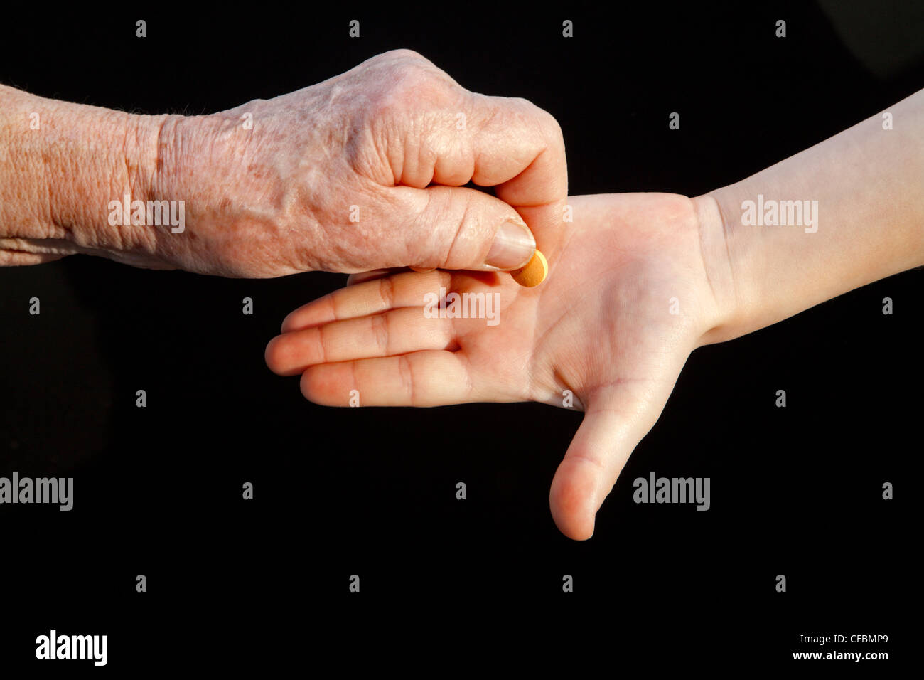 Hand der Großmutter und Enkel mit einer Pille Stockfoto