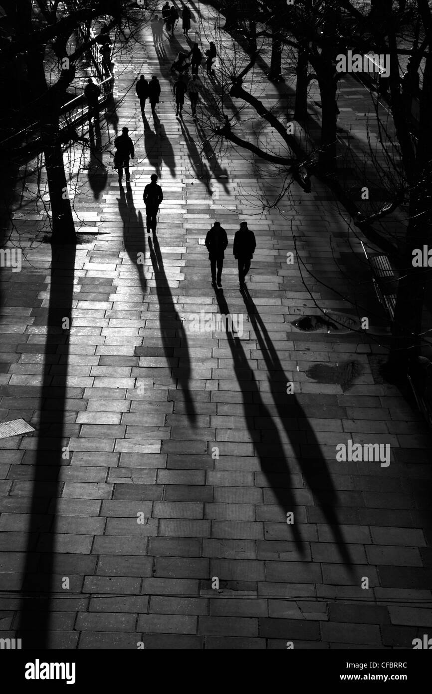 Schatten und Silhouetten der Fußgänger zu Fuß entlang der Königin Spaziergang entlang der Themse in South Bank, London, UK Stockfoto