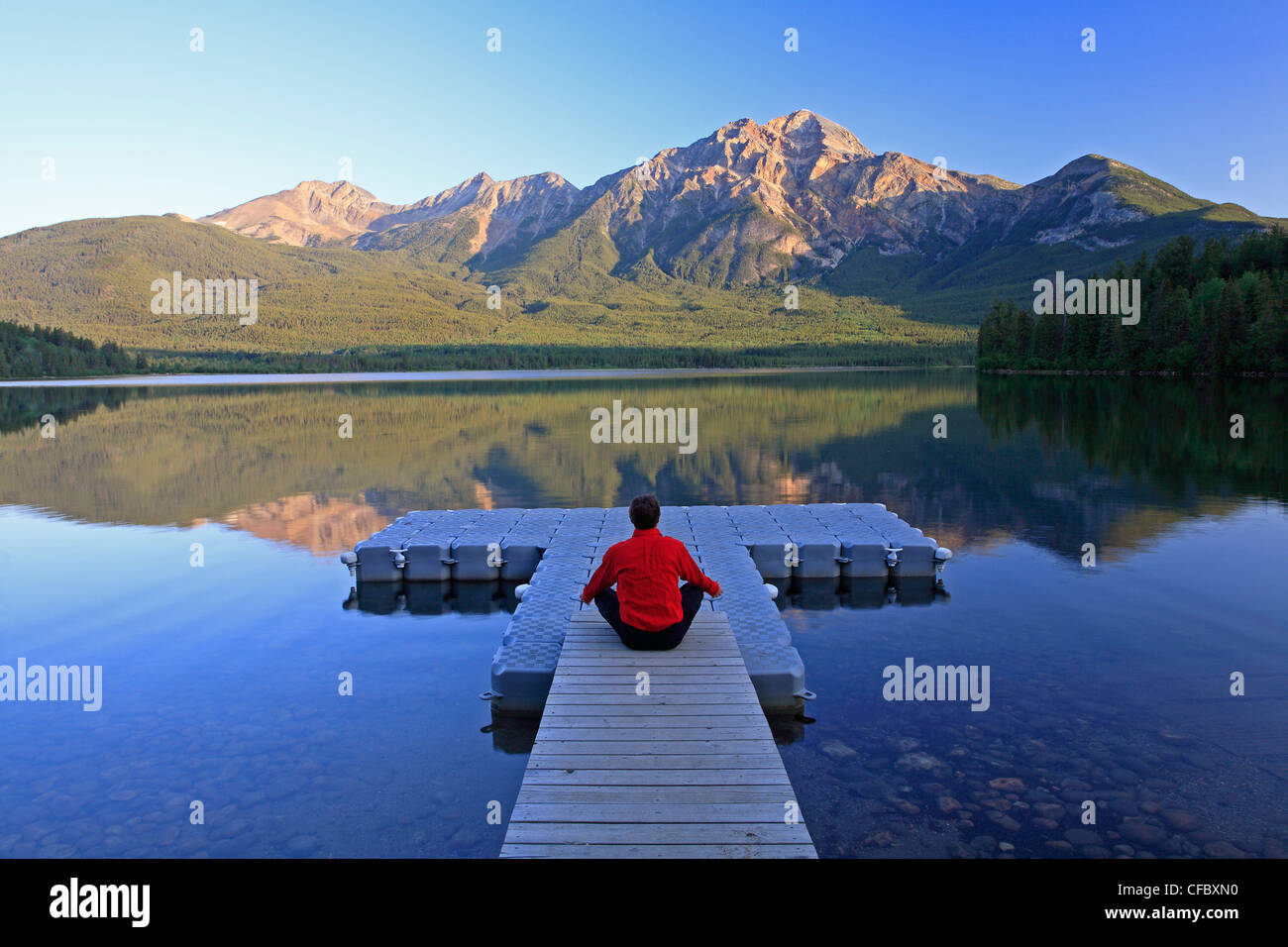 Mittleren Alters männlichen meditieren auf dock am Pyramid Lake, Jasper Nationalpark, Alberta, Kanada. Stockfoto