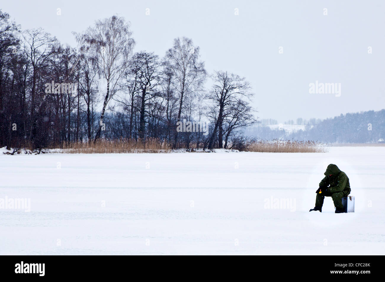 Mann Angeln in das gefrorene Wasser des Lake Galve in Trakai, Litauen (schwarz und weiß erhältlich bei CFC288) Stockfoto