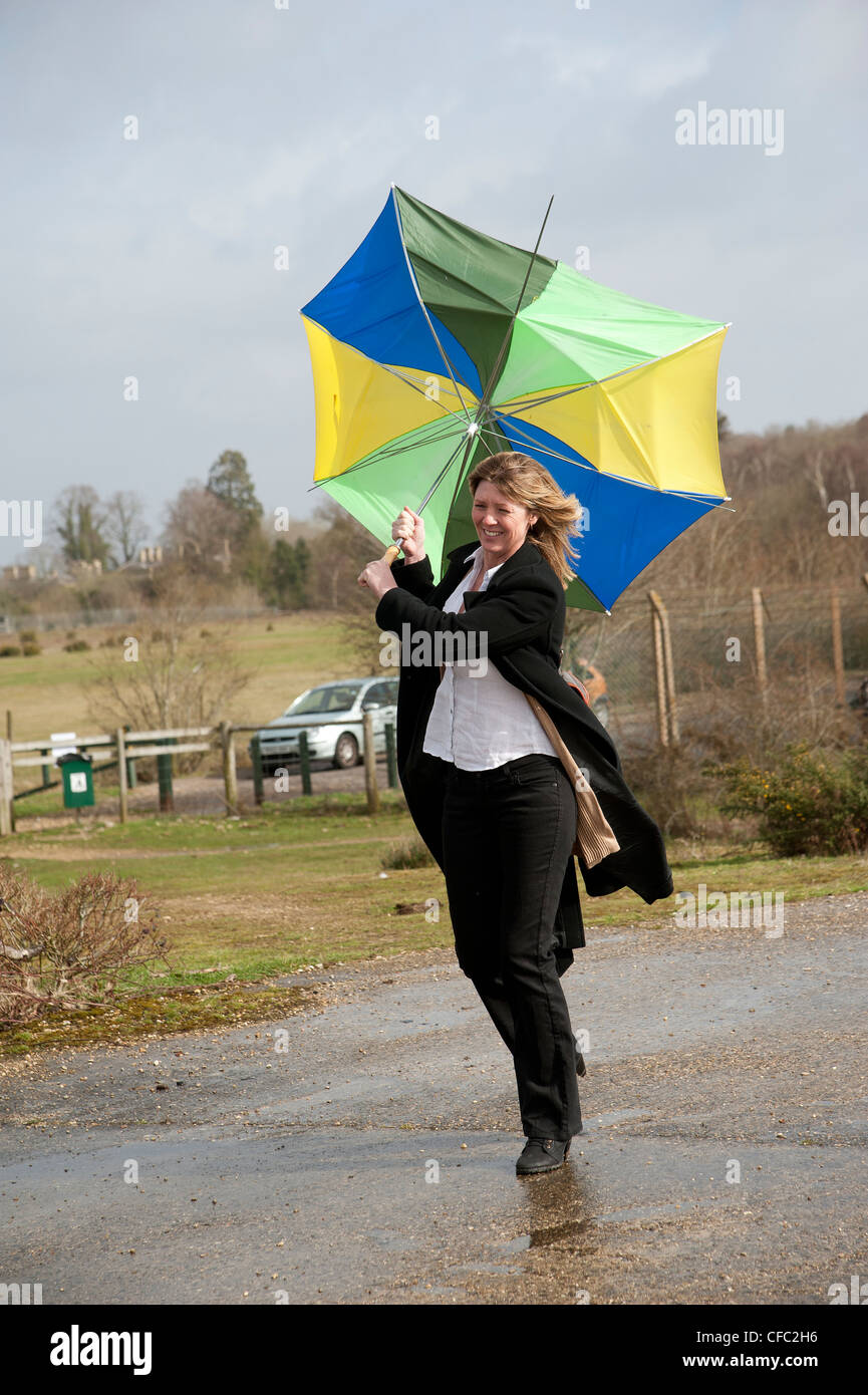 Frau kämpft, auf ihrem Schirm bei starkem Wind zu halten Stockfoto