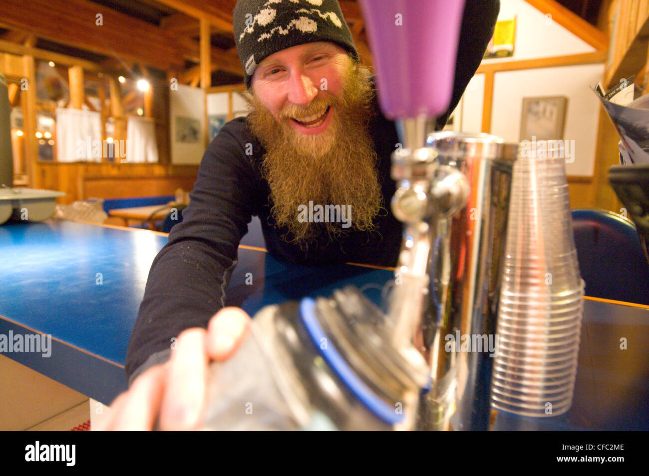 Ein Skifahrer glücklich Hippie füllt seine Wasserflasche mit Bier im Wildwasser Wintersportort, Britisch-Kolumbien Stockfoto