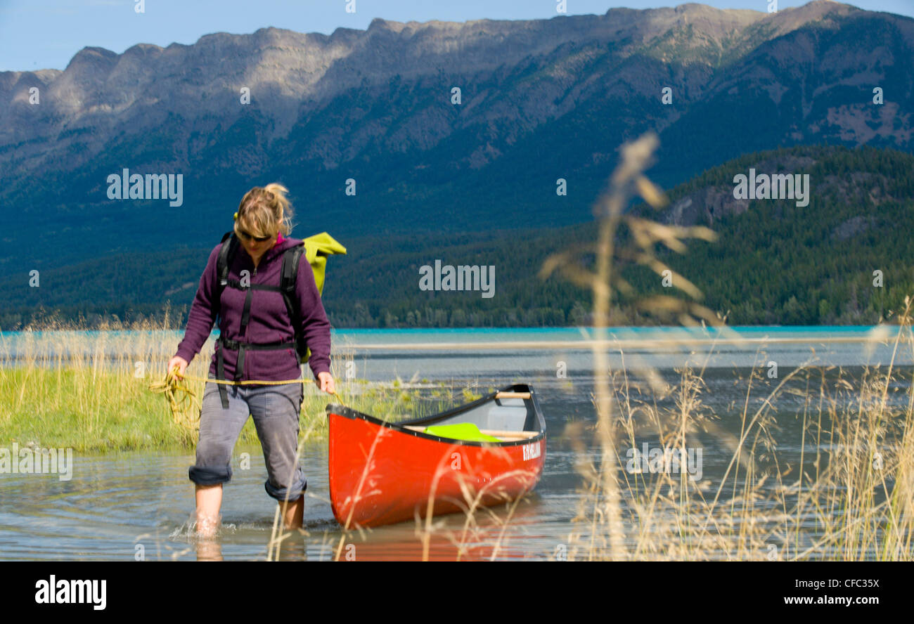 Eine junge, attraktive Frau führt ihr Kanu quer durch das seichte Wasser der Tatla Lake, British Columbia, Kanada Stockfoto