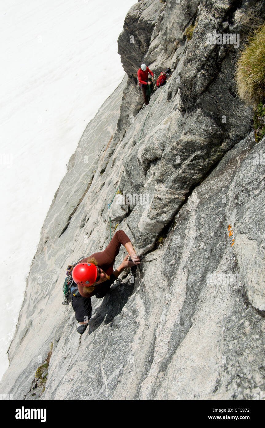 Zwei Kletterer bewältigen die eindrucksvolle Südwand des Asgard Peak in den Bergen von Valhalla, Selkirk Range, British Columbia, Kanada Stockfoto
