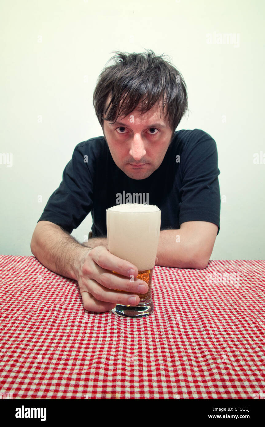 Betrunkener Mann am Tisch mit einem Glas kalten, leichte Bier Pub. Stockfoto