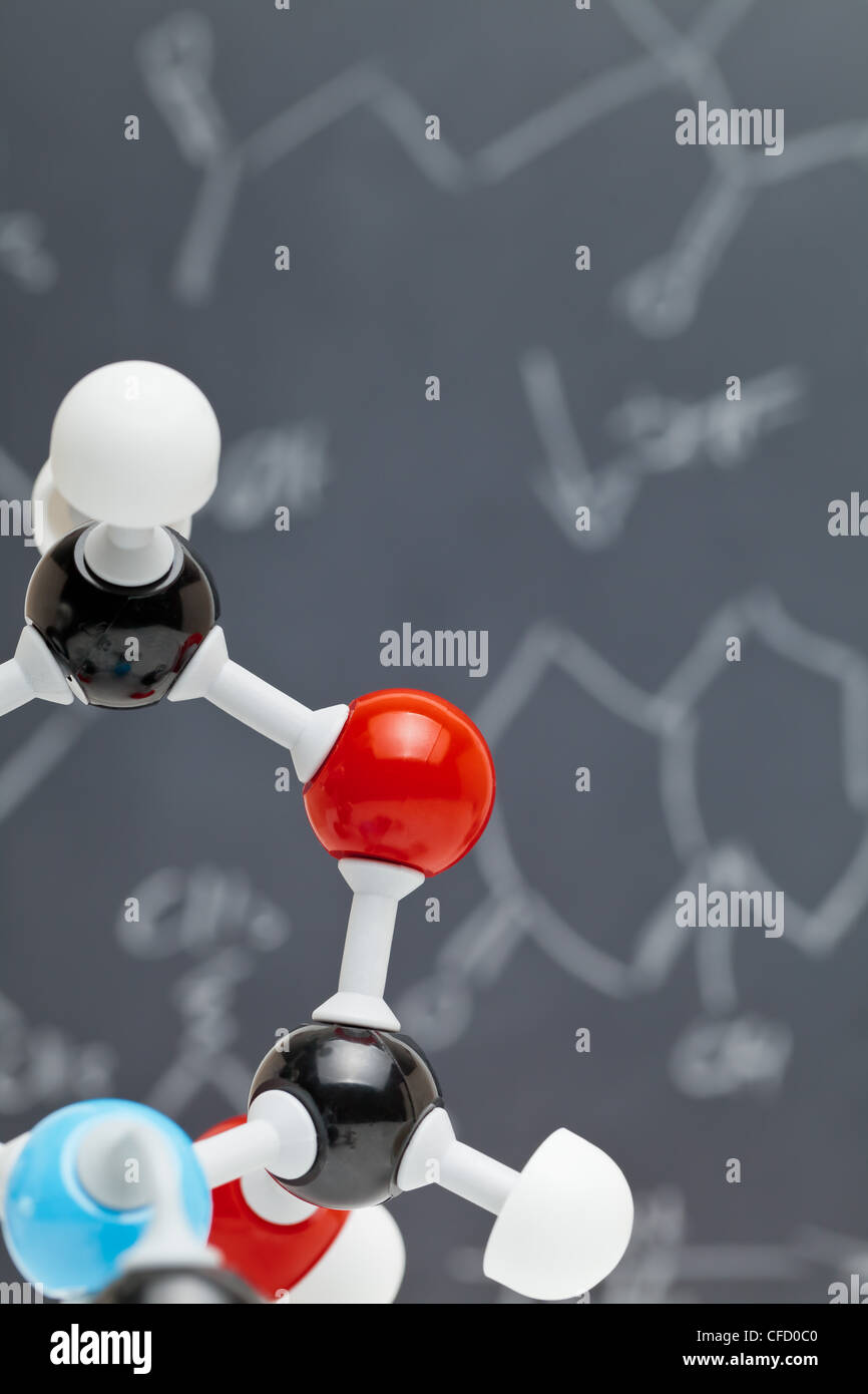 Molekül-Modell mit Formeln auf Tafel im Hintergrund Stockfoto