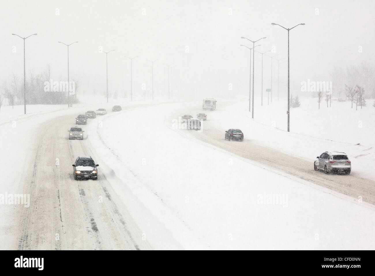 Verkehr auf einer schneebedeckten Straße während eines Schneesturms Winter. Winnipeg, Manitoba, Kanada. Stockfoto