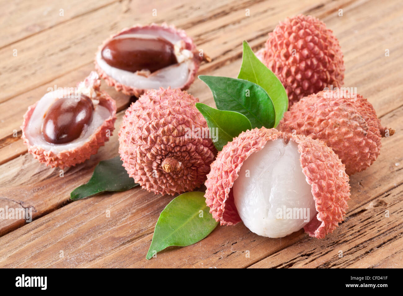 Litschi mit Blätter auf einem Holztisch. Stockfoto