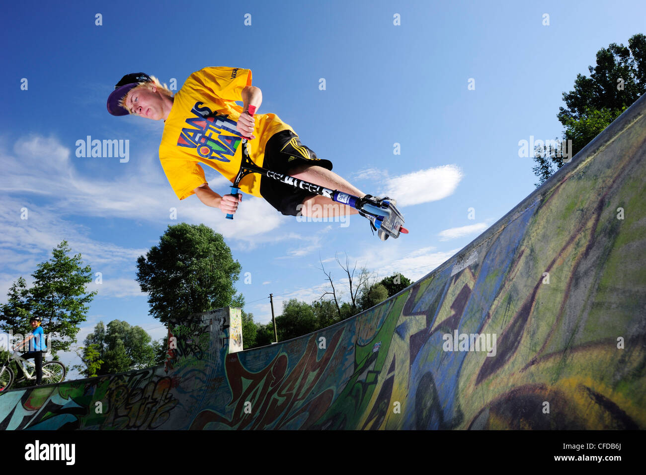 Junger Mann Durchführung Sprung mit Roller, Skatepark, München, Oberbayern, Deutschland Stockfoto