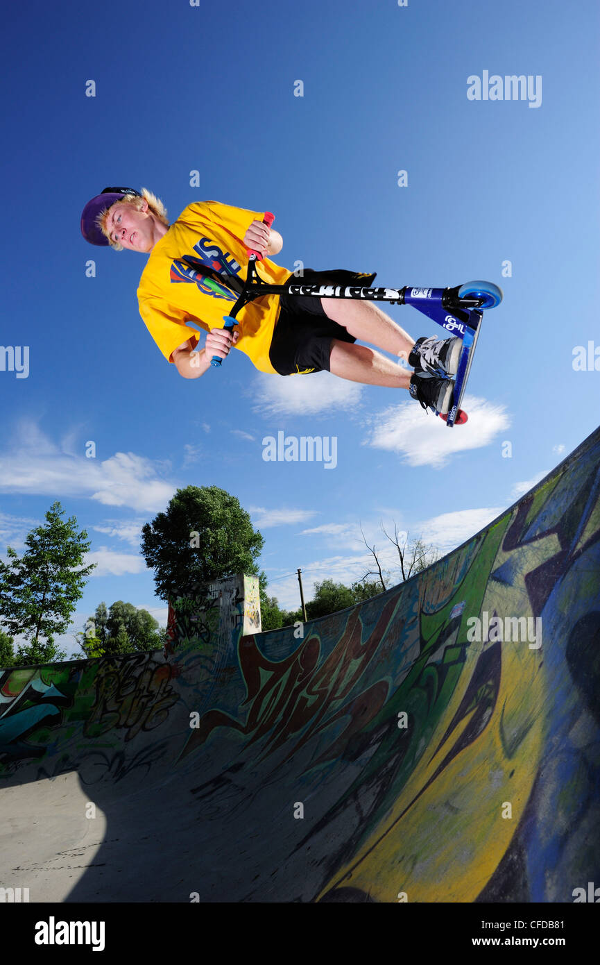 Junger Mann Durchführung Sprung mit Roller, Skatepark, München, Oberbayern, Deutschland Stockfoto