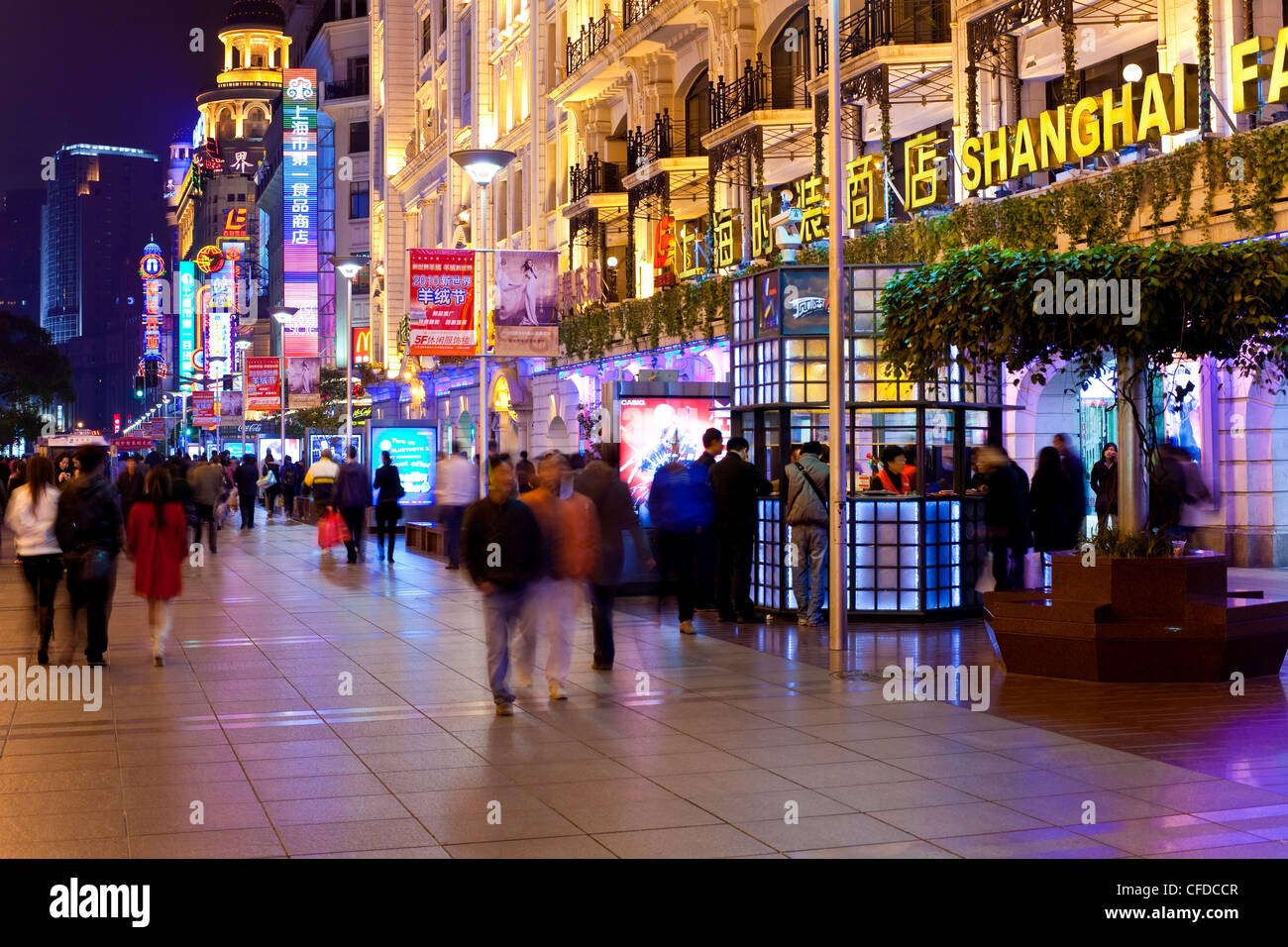 Fußgänger in der Nacht zu Fuß vorbei an Geschäften auf Nanjing Road, Shanghai, China, Asien Stockfoto