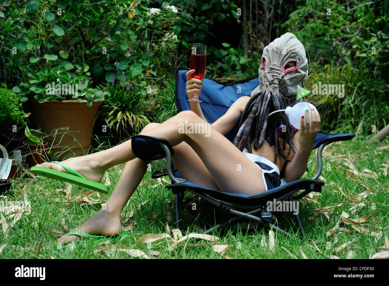 10 Jahre gekleidet altes Kind in selbst gebastelten Ood Maske, draußen in der Sonne bei einem Drink entspannen. Stockfoto
