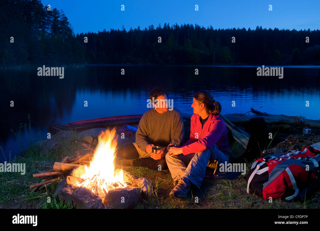 Junges Paar sitzt am Lagerfeuer am Abend, See Ottenstein, Niederösterreich, Österreich, Europa Stockfoto