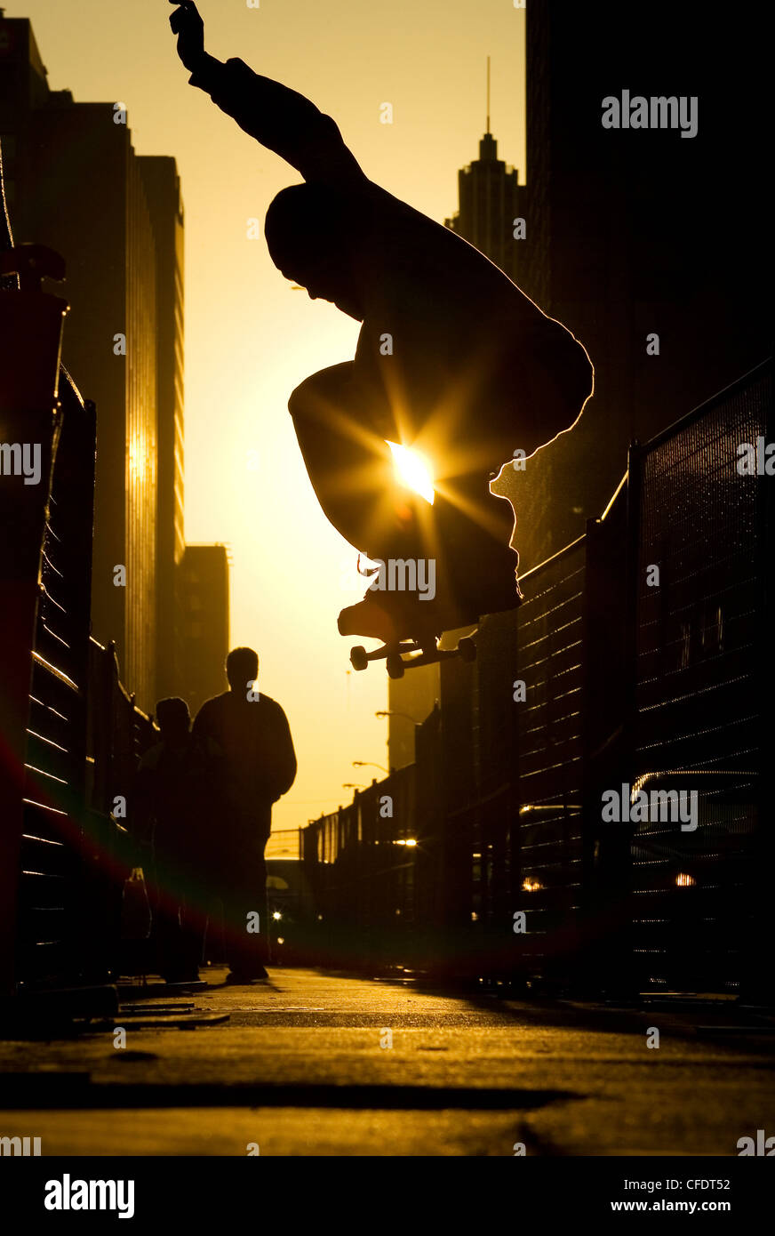 Ein Skateboarder tut ein "Ollie" entlang einer Straße in der Innenstadt von Toronto bei Sonnenuntergang, Ontario, Kanada. Stockfoto
