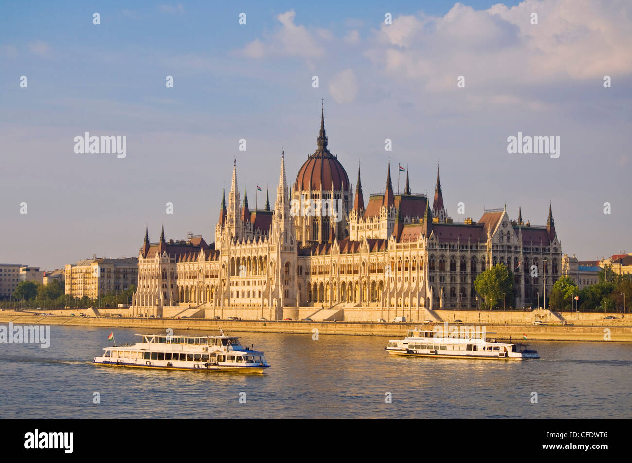 Das ungarische Parlamentsgebäude, mit Kreuzfahrt-Schiffe auf der Donau im Vordergrund, Budapest, Ungarn Stockfoto