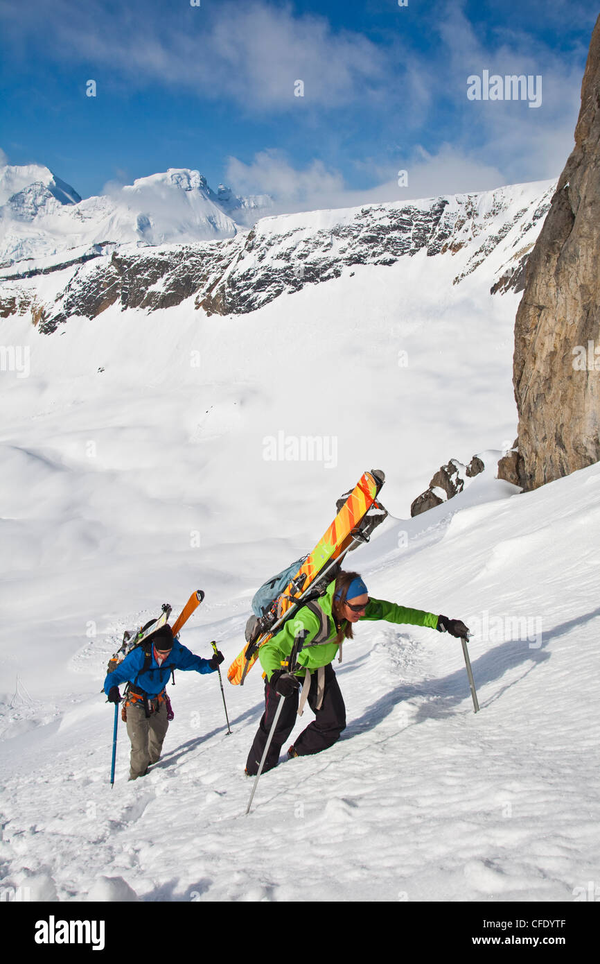 Zwei Backcountry Skifahrer Bootpack, eine Steilwand auf der anderen Seite das Skifahren. Eisfall Lodge, British Columbia, Kanada Stockfoto