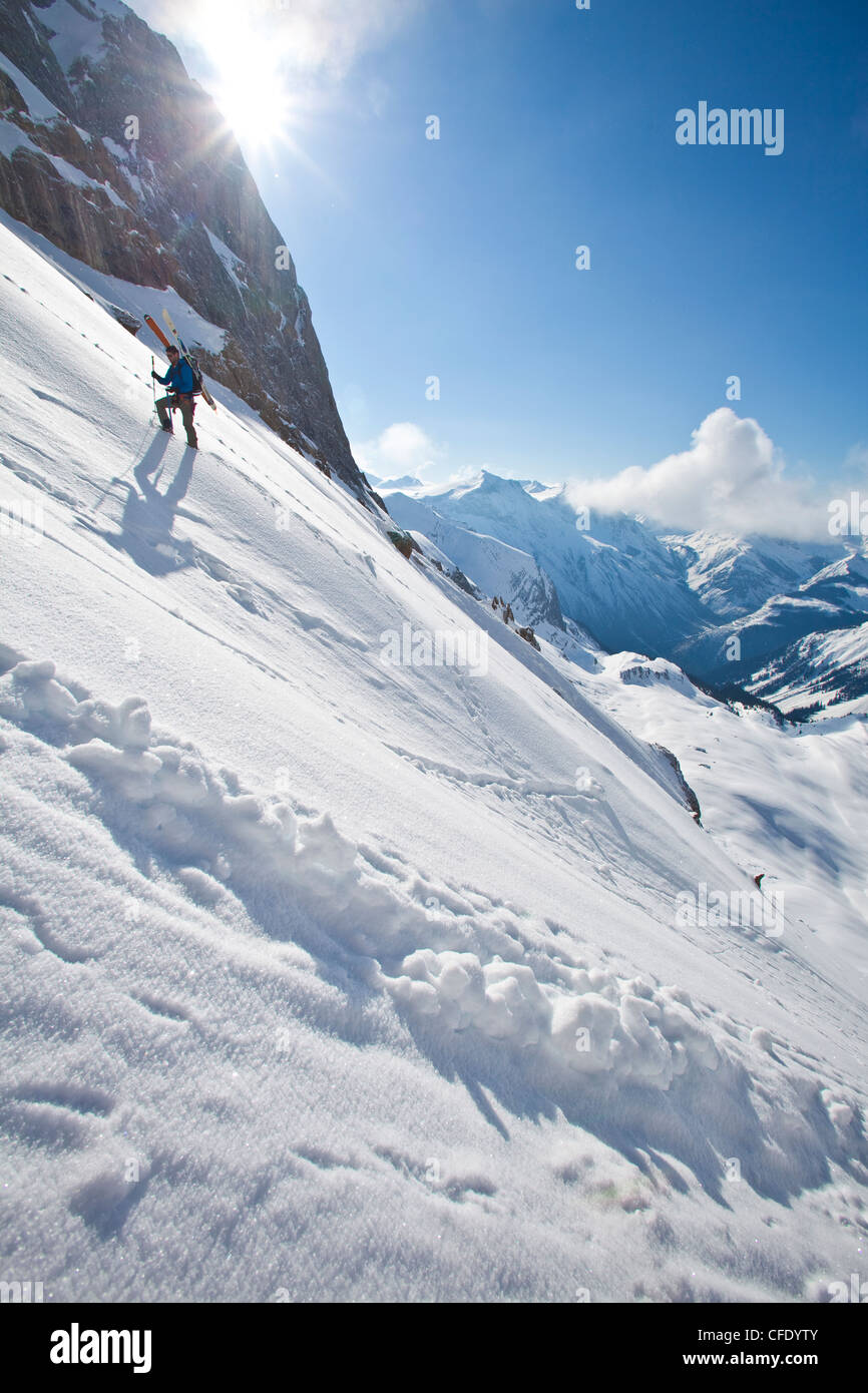 Eine männliche Ski Bergsteiger Bootpacks, exponierte Steilhang. Eisfall Lodge, Golden, British Columbia, Kanada Stockfoto