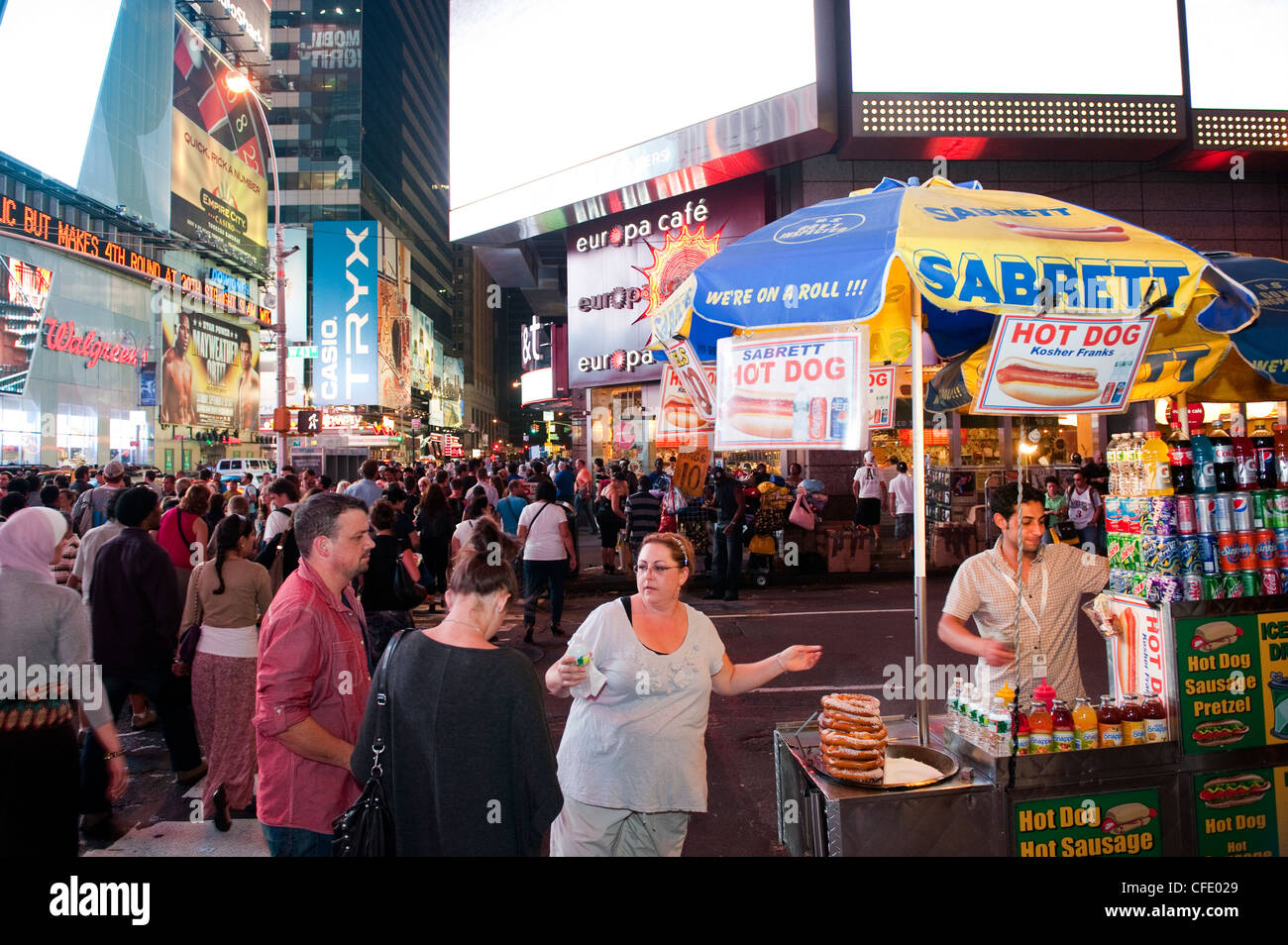 Menschen auf einen Hot Dog stehen in einem belebten Times Square, New York, in der Nacht. USA. Stockfoto