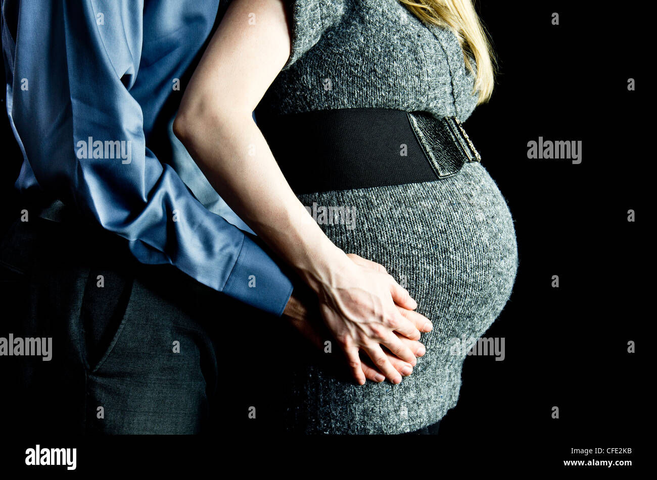 Eine Mutterschaft Bild eines Paares im Hintergrund low-Key, schwarz, Schultern, Hüften nur abgebildet. Stockfoto