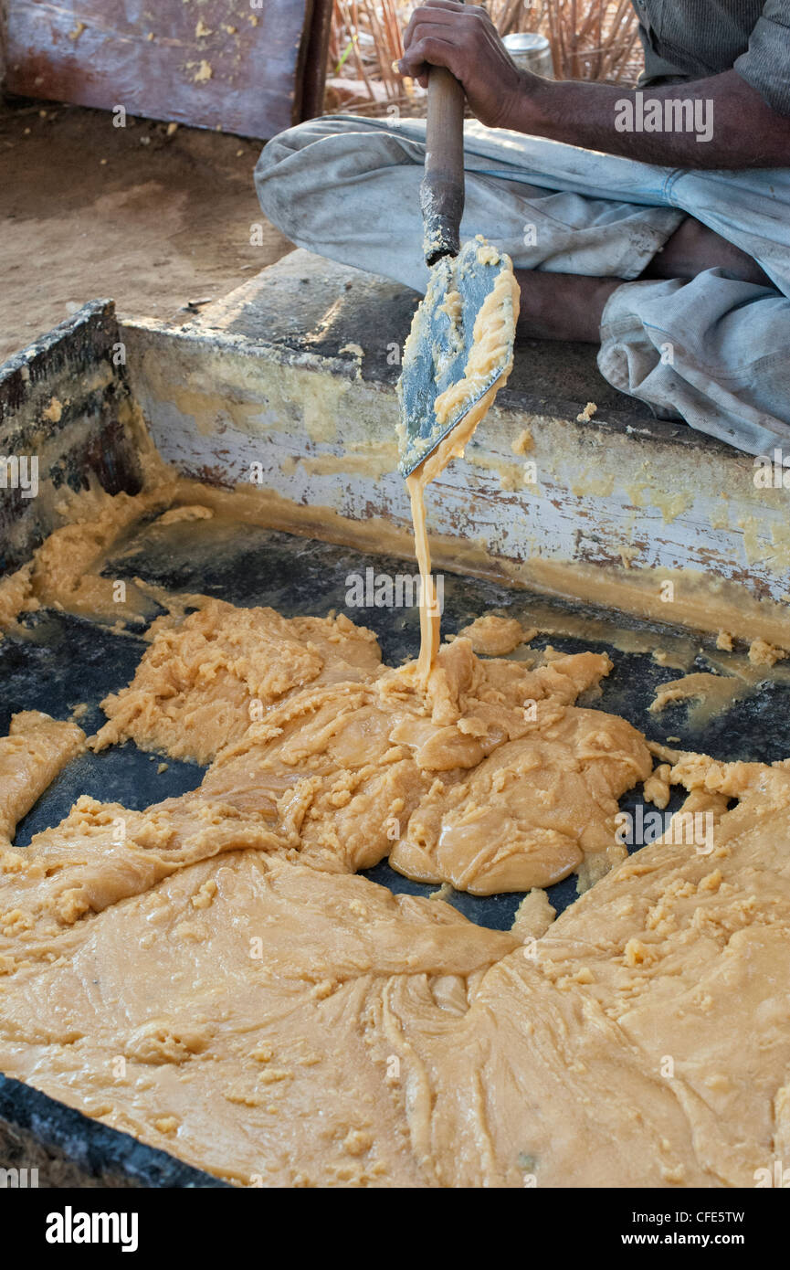 Jaggery Produktion im ländlichen Süden indischen Landschaft. Unraffiniertes Rohzucker in eine Kühlwanne vor dem Walzen. Andhra Pradesh, Indien Stockfoto