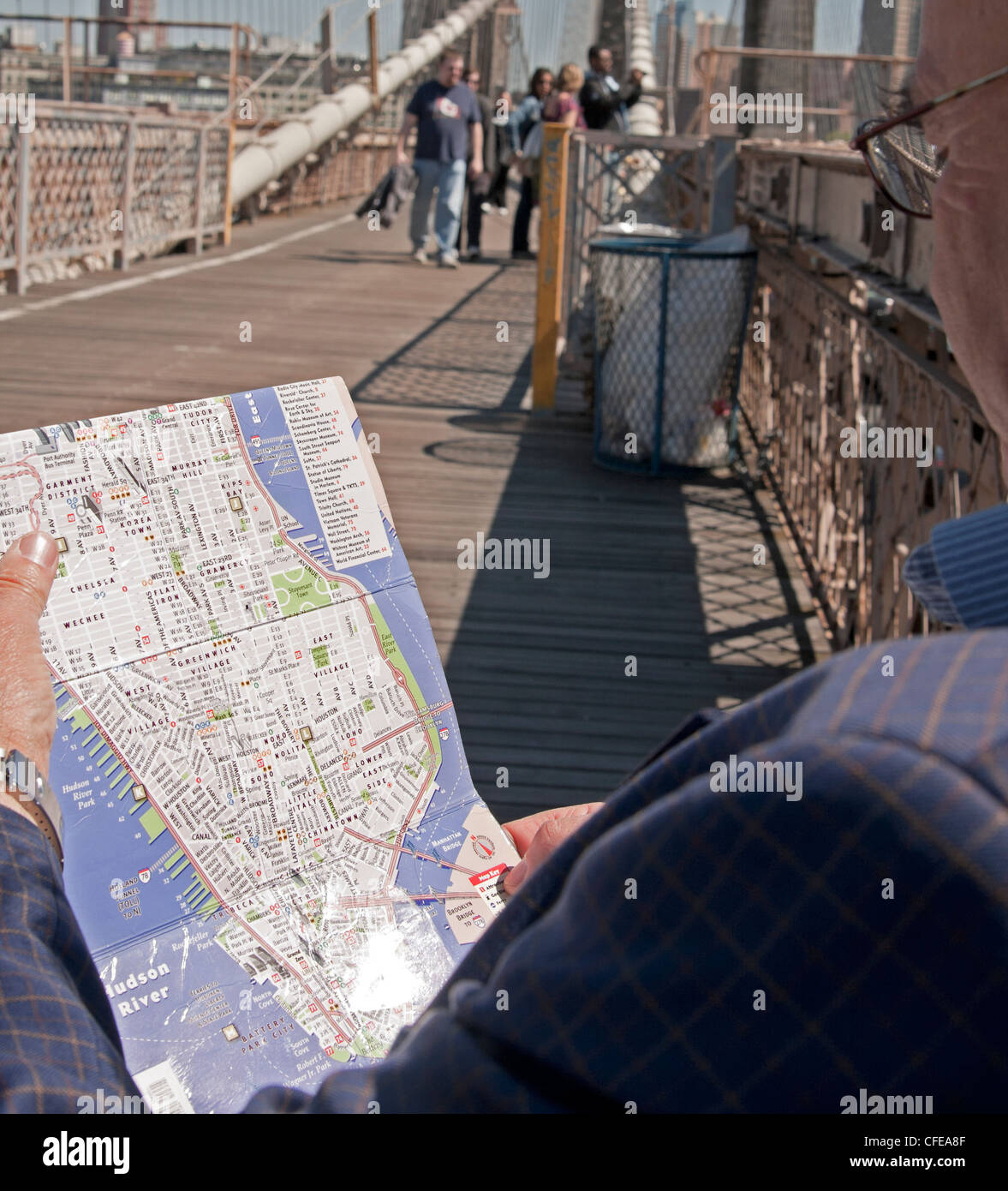 Ein Mann studiert seine Karte von New York City während der Sitzung auf der Brooklyn Bridge. Stockfoto