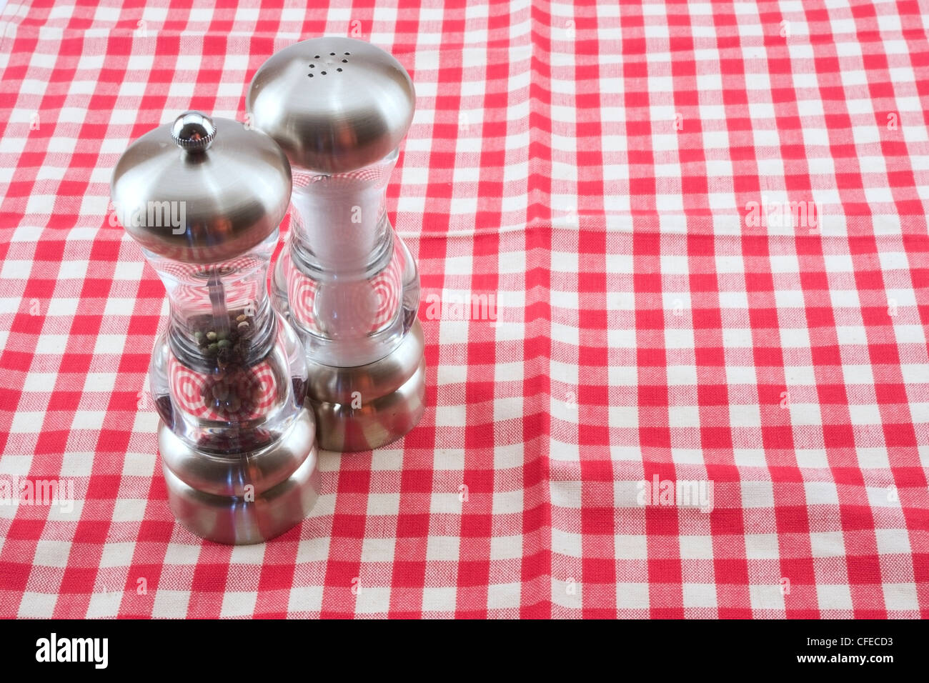 Salz- und Pfefferstreuer auf rot-weiß karierte Tischdecke. Stockfoto