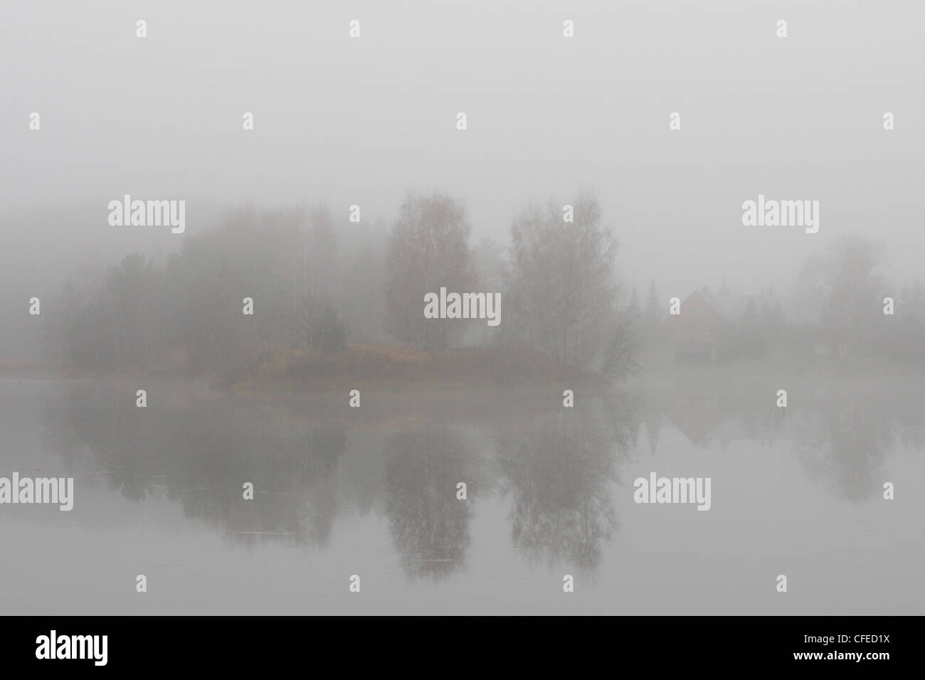 Dichter Nebel am See. Haus auf der anderen Seite des Ufers zu sehen. Stockfoto