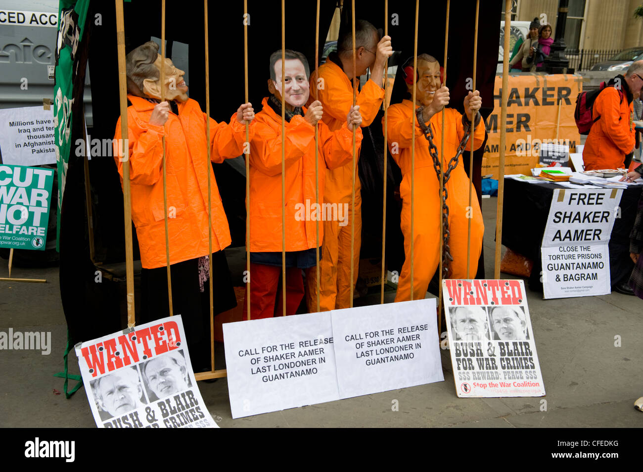 Aktivisten in der Kampagne "Gratis Shaker Aamer" gekleidet in orange Overalls und Masken Pose hinter Gittern Stockfoto