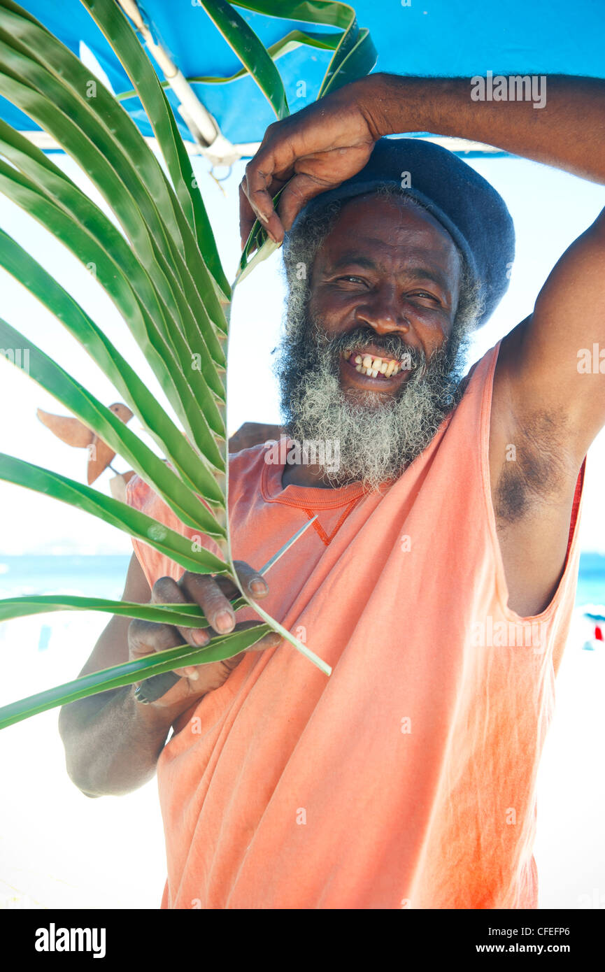 Bärtige lächelnd lokalen Rastafarian schwarzen Hut hält Palm Frond, Orient Beach, Saint-Martin Stockfoto