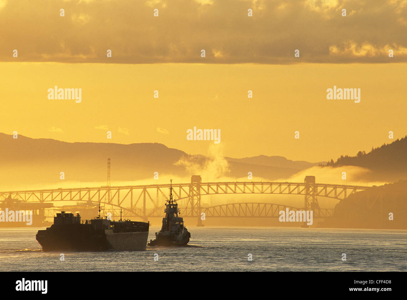 Schlepper mit Barge nähert sich die Eisen Arbeiter Second Narrows Bridge bei Sonnenaufgang, Vancouver, Britisch-Kolumbien, Kanada. Stockfoto