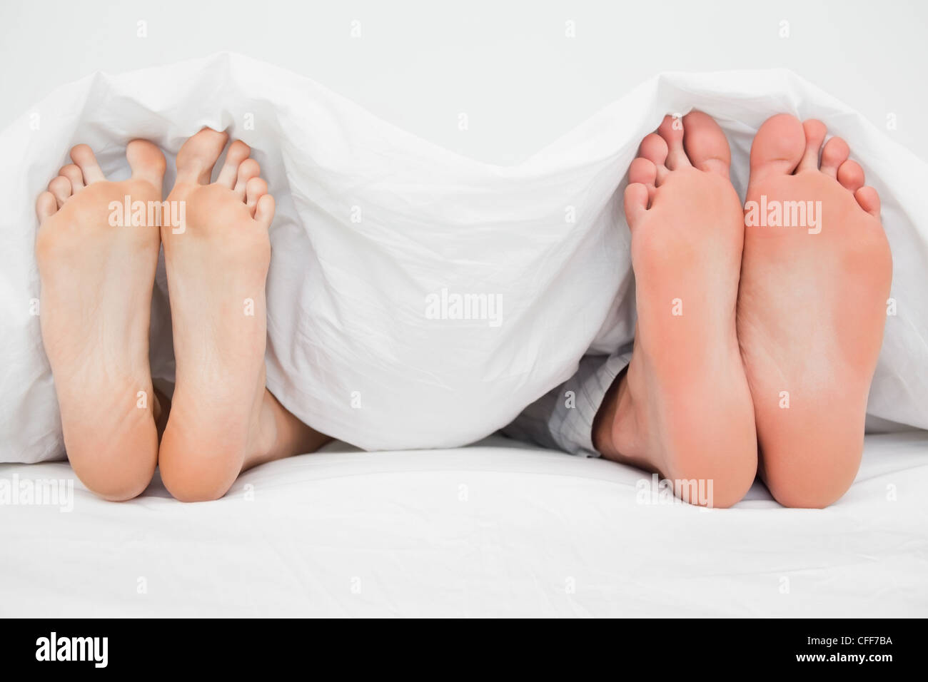 Zwei Paar Füße im Bett neben einander senkrecht nach oben zeigen Stockfoto