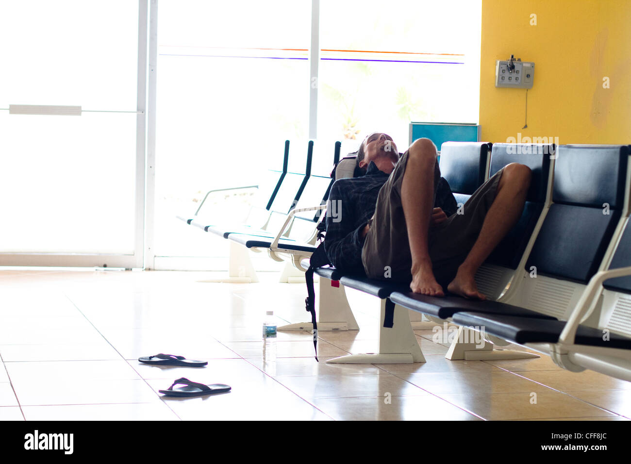 Eine erschöpfte männliche Reisende wartet in einem Flughafen-terminal für seinen Flug nach Ankunft am internationalen Flughafen Manzanillo in Coli Stockfoto