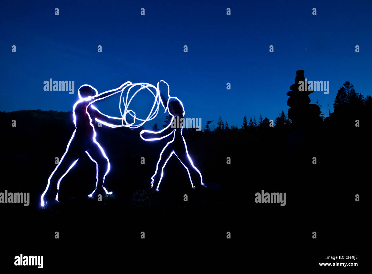Lightpainting zweier Figuren hält eine Kugel aus Licht Energie bei Sonnenuntergang in Idaho. Stockfoto