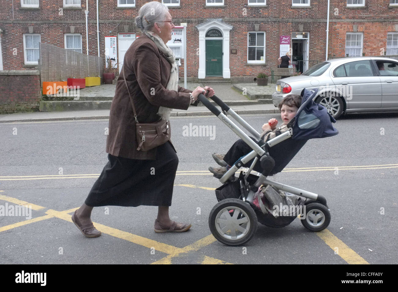 Eine Dame in ihren Sechzigern schiebt einen Kinderwagen in Falmouth, England Stockfoto