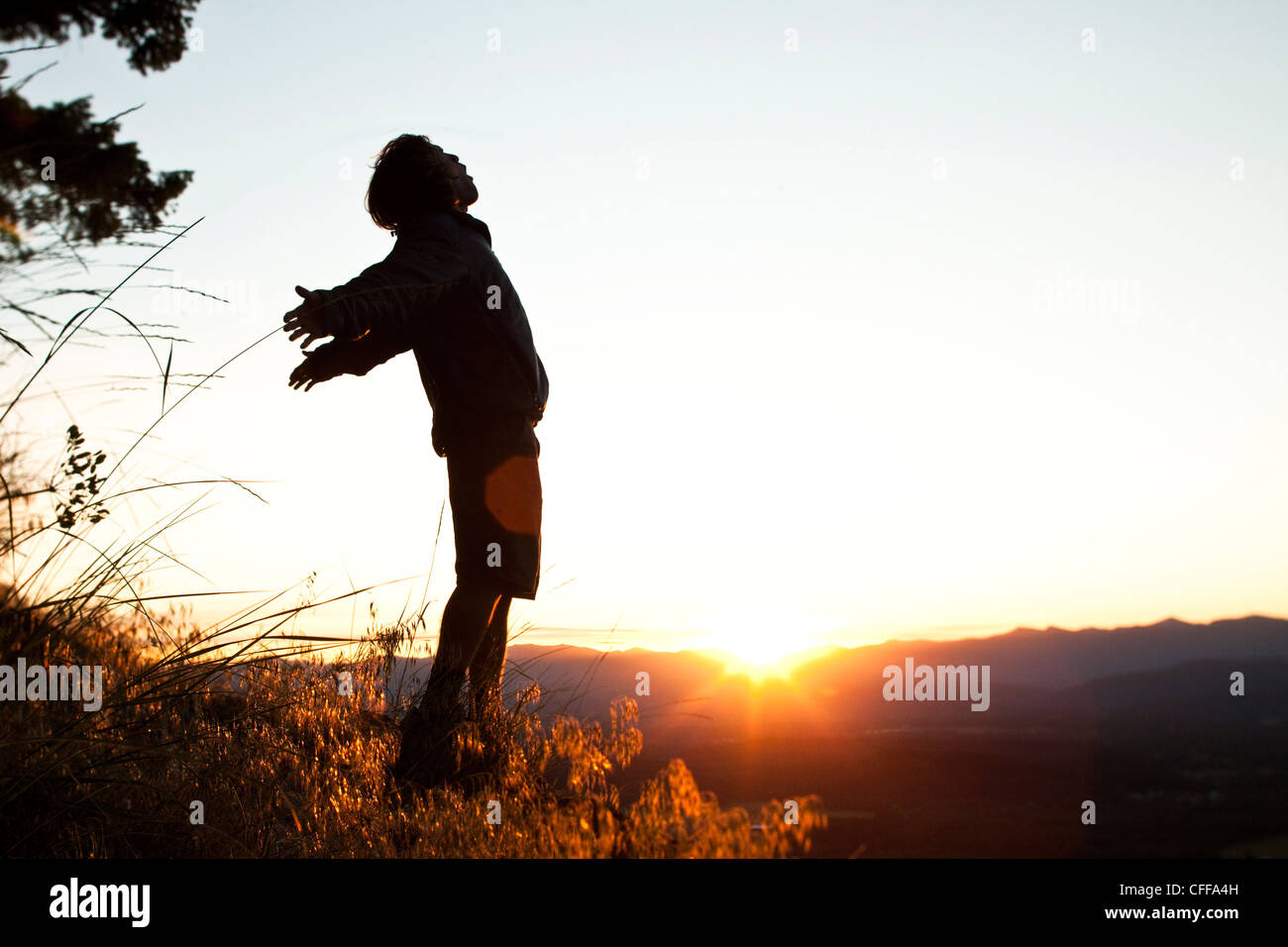 Ein junger Mann empfängt am Morgen bei einer Wanderung als die Sonnenaufgänge über ein Tal in Idaho. Stockfoto