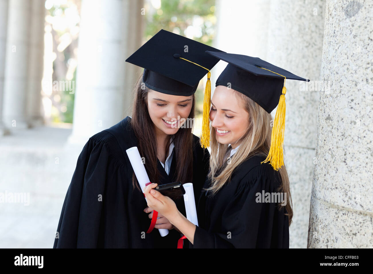Lächelnd Absolventen einer Digitalkamera während stehend betrachten Stockfoto