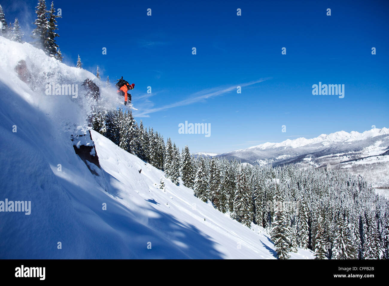 Einem sportlichen Snowboarder springen von einer Klippe auf einer sonnigen Powder-Tag in Colorado. Stockfoto