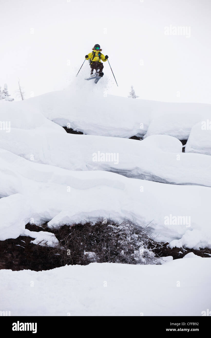 Eine Skifahrerin, von einer Klippe zu springen an einem stürmischen Tag in Colorado. Stockfoto