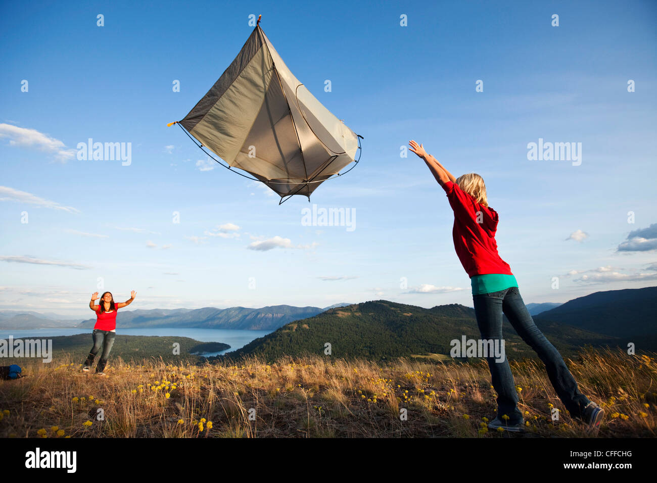 Zwei Frauen ein Zelt bei Sonnenuntergang auf einem camping-Ausflug über dem See in Idaho zu werfen. Stockfoto