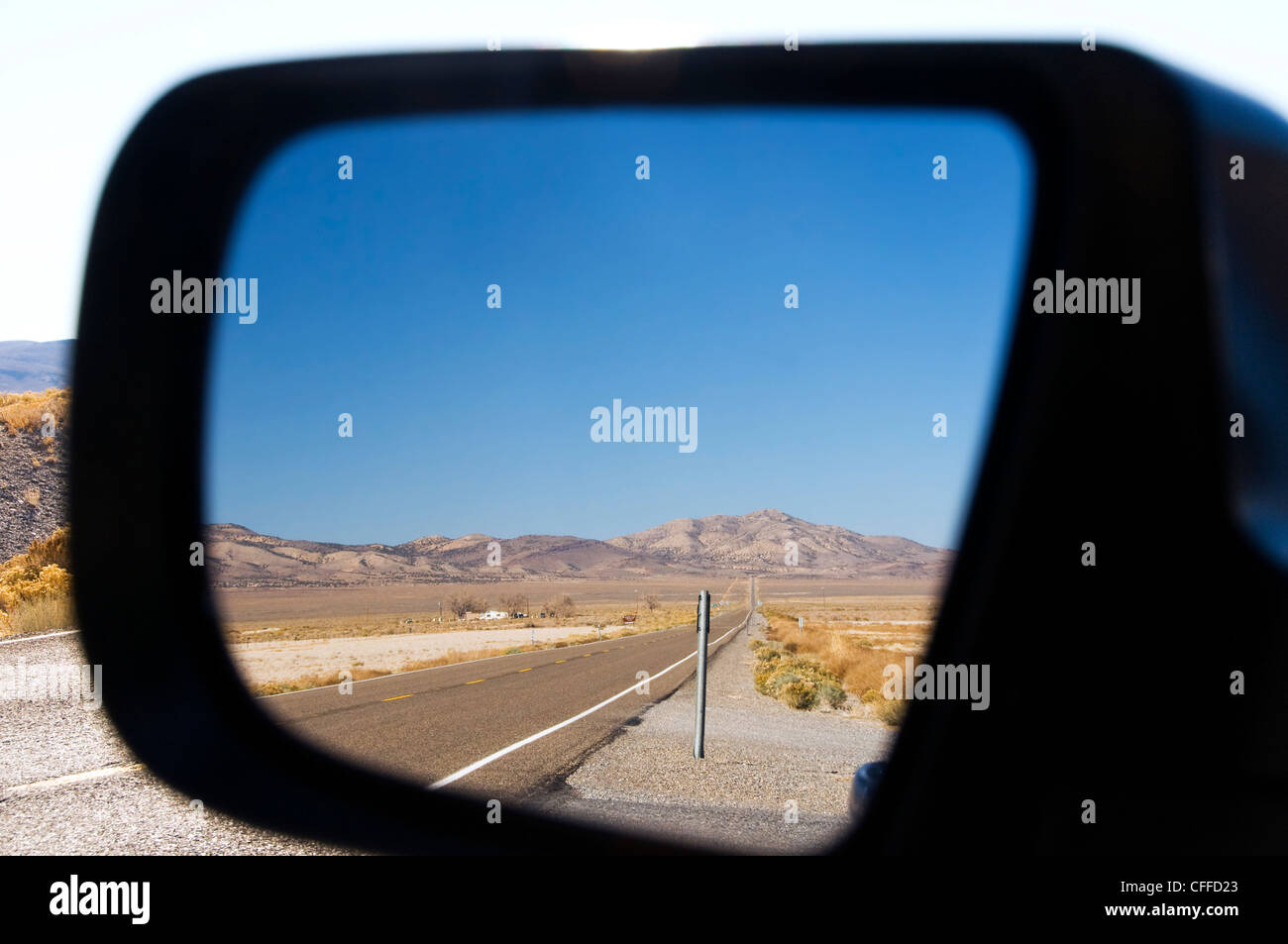 Highway 50 in Nevada, besser bekannt als die Loneliest Road in America, spiegelt sich in einem Rückspiegel. Stockfoto