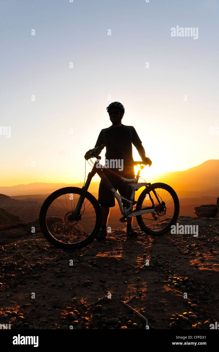 Eine Silhouette eines Mountain-Bikers bei Sonnenuntergang am Stachelbeere Mesa im südlichen Utah. Stockfoto