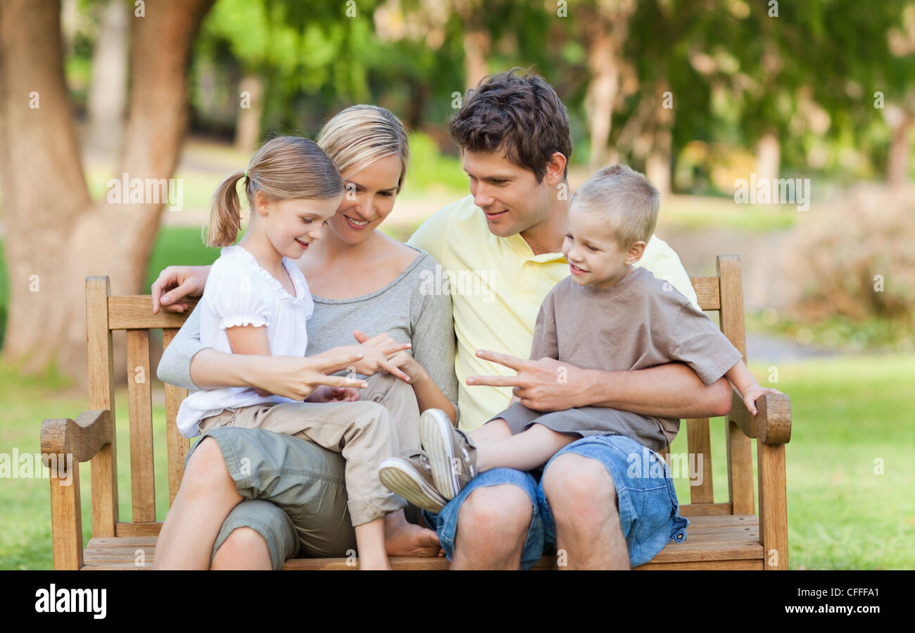 Die ganze Familie sitzt auf der Parkbank Stockfoto