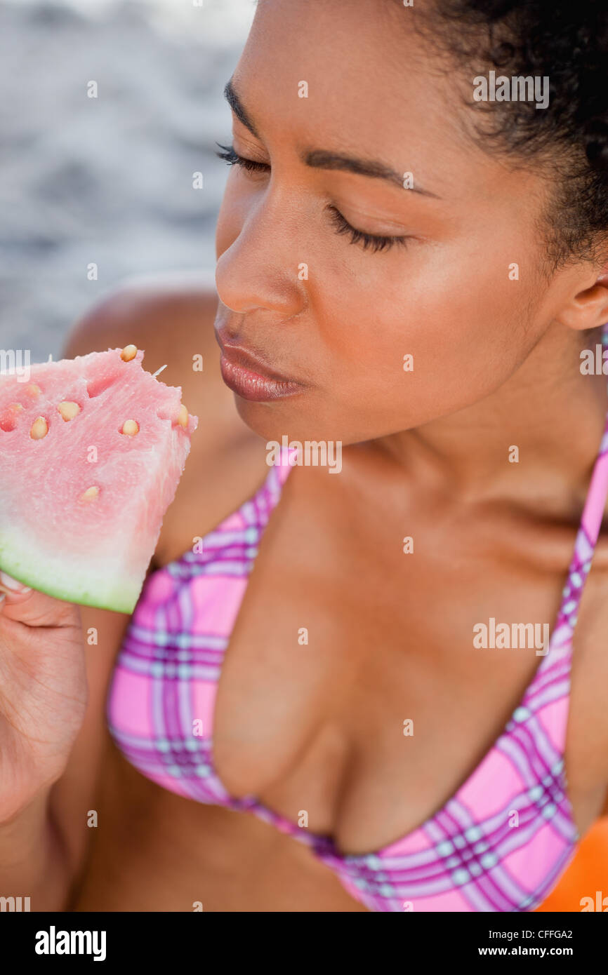 Junge Frau, die ihre Augen zu verschließen, während des Essens ein Stück Wassermelone Stockfoto