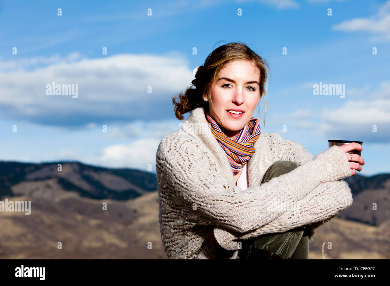 Eine junge Frau Kaffee nippt und posiert in geschichteten Outdoorbekleidung in Fort Collins, Colorado. Stockfoto