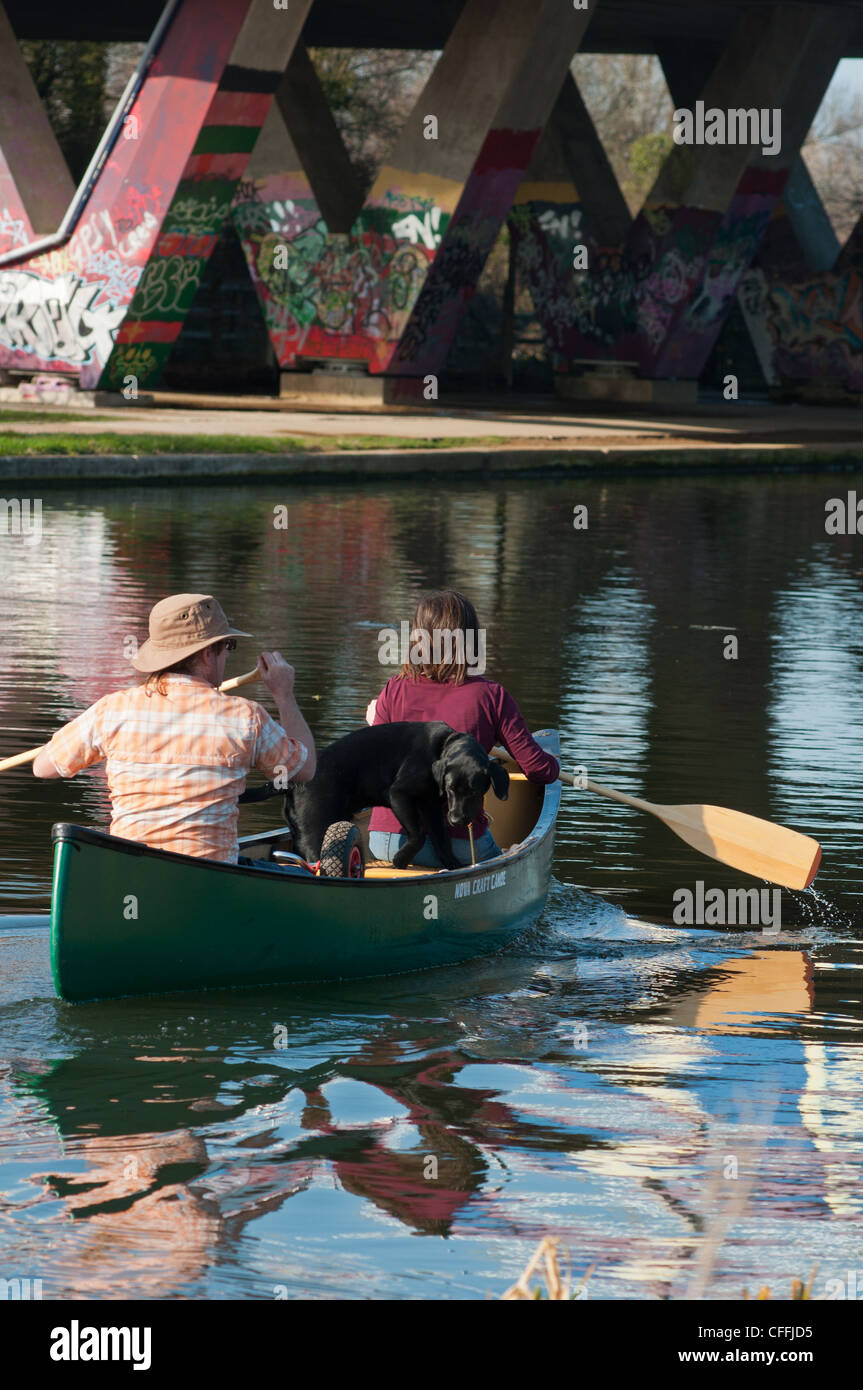 Zwei Personen und ein Hund Kanu fahren Sie unter der A 14 Brücke auf dem Fluss Cam. Cambridgeshire. England. Stockfoto