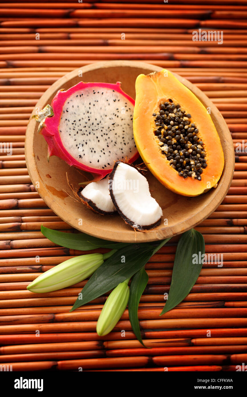 Drachenfrucht, Papaya und Kokosnuss in Holzschale auf Bambus-Hintergrund Stockfoto